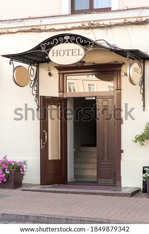 entrance door with a threshold and a visor with a hotel sign on the facade of the building with a flowerpot, european cityscaep nobody.