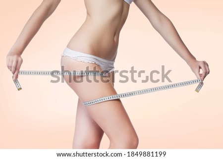 Woman measuring her thigh using a tape measure