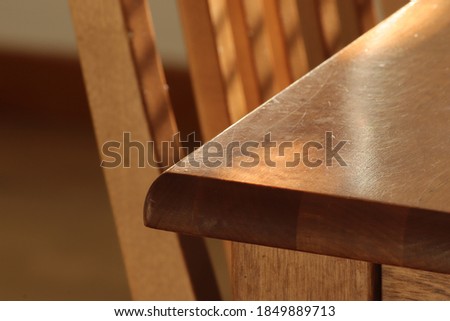 An abstract close up of a corner a worn and scratched dark brown oak table