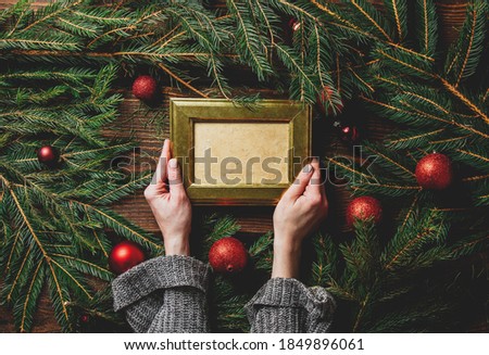 Female hands hold photo frame next to Christmas decoration 