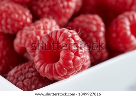 Close-up photo of raspberries in a white bowl.