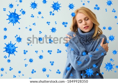 Stronger immunity - better disease resistance. Young woman wearing warm blue sweater surrounded by viruses on light background Royalty-Free Stock Photo #1849928350