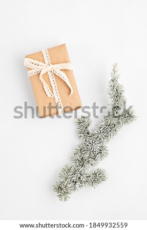 Christmas tree branch and gift box wrapped in organic craft paper on white background, flat lay, top view, copy space. Winter holidays, xmas greeting card