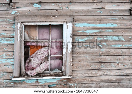 An image of an old broken window with peeling paint on an abandon building.