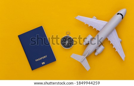 Minimalism travel, adventure flat lay. Compass and air plane, passport on yellow background. Top view