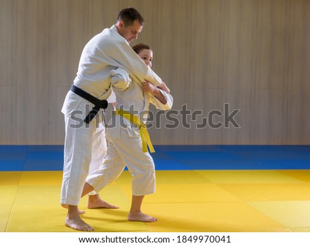 Young female yellow belt judoka setting up older black belt male judoka for throw Royalty-Free Stock Photo #1849970041