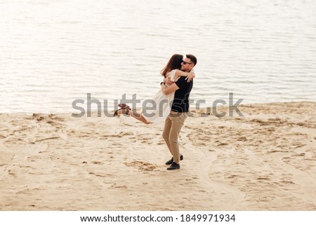 Romantic couple is hugging and having fun outdoors. elegant and stylish woman and man in love are walking along the lake. Happy moments together. love story