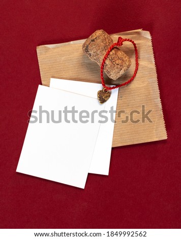 Burgundy cardboard. White sheets of paper. A cork from champagne. A Kraft paper envelope. Notes to a friend. Decorative heart on a string. Space for text. Love letter. Love relationship.
