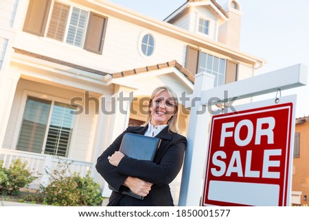 Female Real Estate Agent in Front of For Sale Sign and Beautiful House.