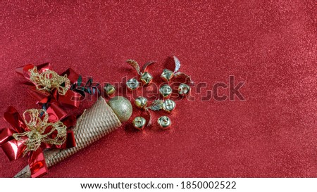 Christmas red sparkle background with waffle gold cone, golden baubles and festive decorative flowers. Banner photo, top view. Nice design for party invitation or greeting card. 