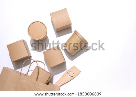 Cardboard containers for food, drinks, items, kitchen spatula with symbolic smile outside the paper bag. White background. Copy space. Delivery, takeaway, zero waste, eco production packaging concept