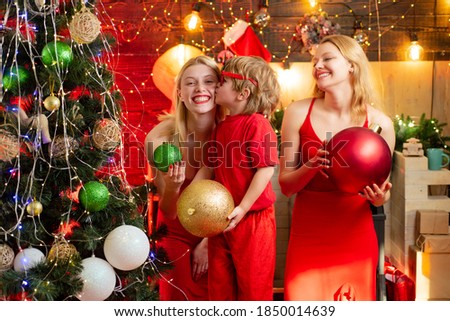 Happy Christmas family. Two young blonde girls in red dress play with little boy and have great time. Childhood memories. Family winter holidays and people concept. Christmas attributes