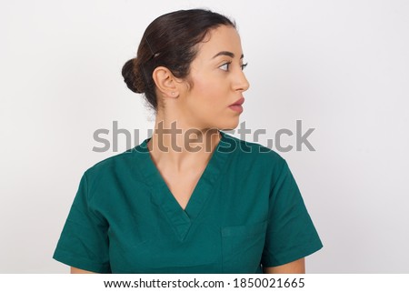 Close up side profile photo Young arab doctor surgeon woman over isolated white background not smiling attentive listen concentrated