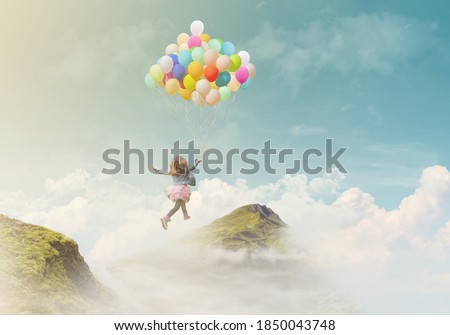 Little girl holding colorful balloons, jumping from one mountain top to the other; success/achievement concept, fantasy background with copy space 
