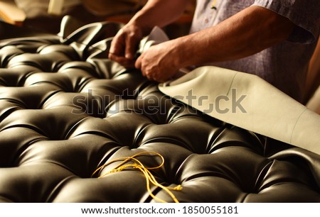 hands working on the upholstery of a capitoned headboard Royalty-Free Stock Photo #1850055181