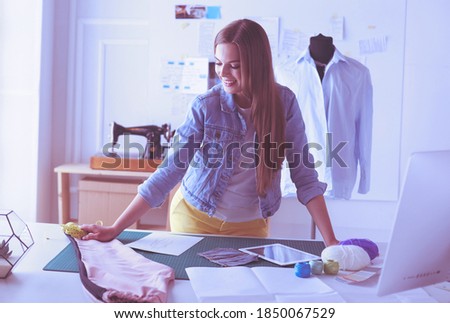 Fashion young designer woman measuring a dress.