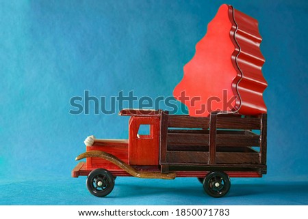 Christmas toy truck with gift box in the form of christmas tree. isolated on blue background. merry christmas and happy new year.