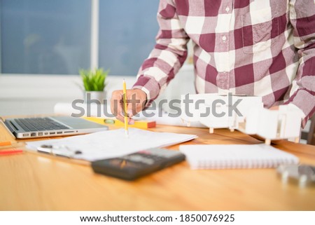 architect man with Architectural plans Laptop, calculator pencil pen and ruler on the table, Concept architects, engineer compass equipment on the desk with a blueprint in the office,Selective Focus