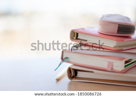 stylish designed coral and white coloured stack of diaries with gold pen. Organiser and planner addicted people. Choosing and sorting journals.