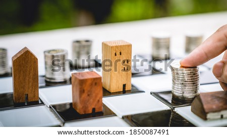 Hand touch stacks of coin money on chess broad with blur wood house model background, Real Estate market, Trading Estate, Mortgage Concepts