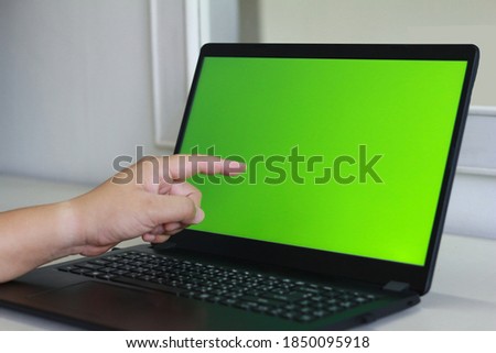 Finger touching Green at Green gradient black laptop's screen.