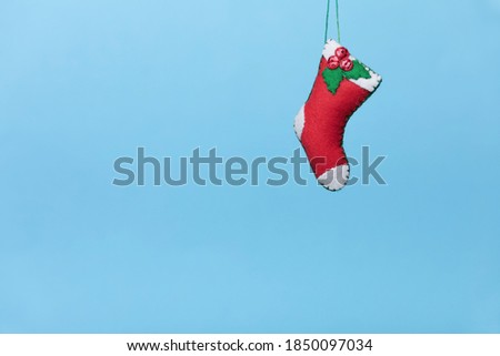 Handmade ornament shaped Red and White Empty Stocking  is on a blue background. The concept of a creative Christmas and new year, blank for advent calendar. Copy space.