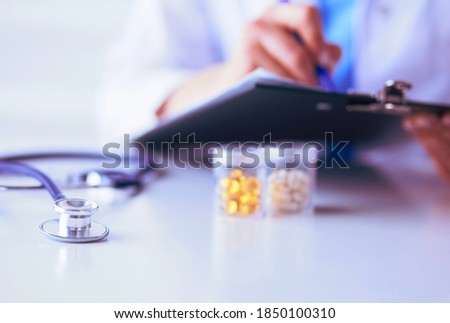 Woman's hands writing on sheet of paper in a clipboard with pen isolated on desk