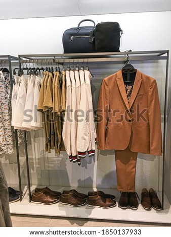 Close up row of jacket, shirt,, brown suit ,pants, and brown shoes are hanging in the shop

