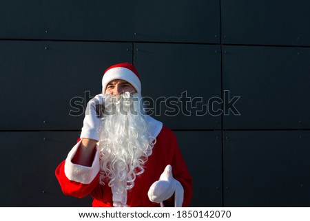 Modern Santa Claus talking on the phone. Ordering the services of an animator for the Christmas and new year. Online greetings via the Internet and mobile communication, social distance