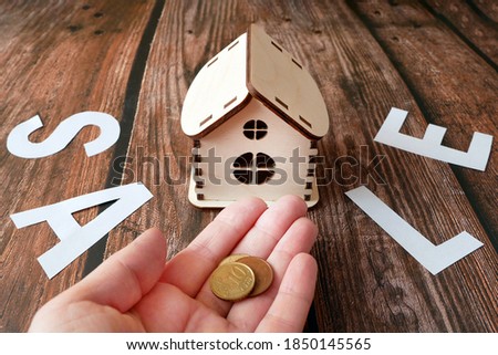 house model on sale with money on wooden background, house for sale concept, closeup