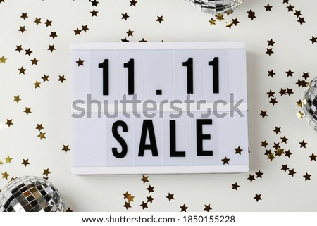 11.11 sale text on white lightbox, small stars and disco balls on white background. Online shopping, singles day sale concept. Top view copy space 