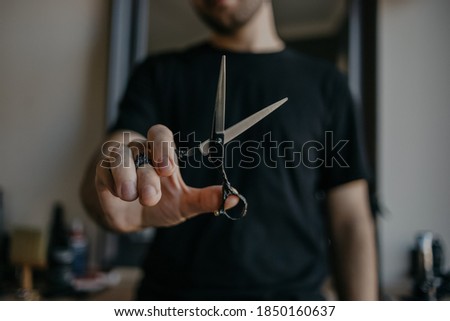 male hairdresser holds scissors in his hands. Barbershop details. Haircut .Selective focus . Blurred