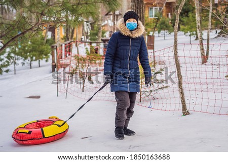winter, leisure, sport, friendship and people concept - woman and snow tubes wearing a medical mask during COVID-19 coronavirus