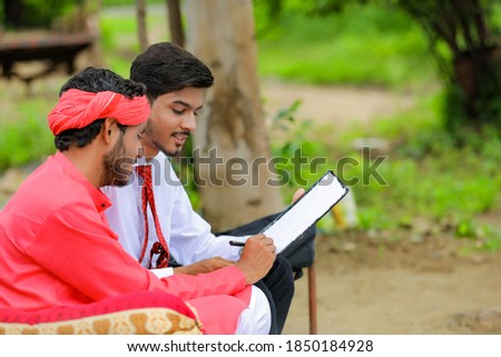 Young indian farmer sign on document with banker at home