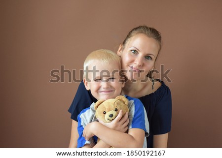 Mother’s Day. Mom and son smile and hug.mother and son on a brown background isolated. A blond boy in his mother's arms. lifestyle. Happiness of motherhood. European appearance. smiles. holiday