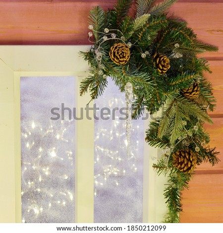 Decorating the window of a wooden house with a Christmas tree branch before the new year