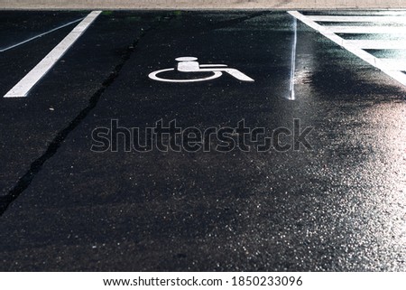 Disabled parking sign painted on dark asphalt at night