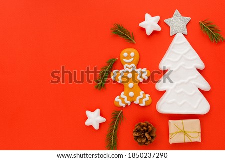 A gingerbread man is located on a red background along with gifts and a Christmas tree. Christmas New Year concept. There is a place for text.