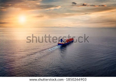 Aerial view of a container cargo ship sailing over calm sea into the sunset Royalty-Free Stock Photo #1850266903