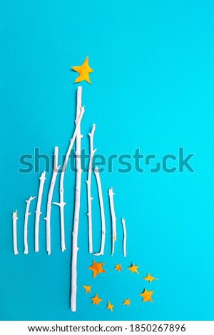 Christmas tree made of white wooden branches on a blue background top view. Festive composition of branches and Christmas decorations flat lay