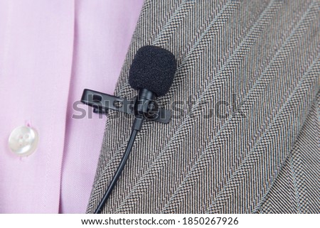 clip-on lavalier microphone is attached to women's clothing close-up. Audio recording of the sound of the voice on a condenser microphone.