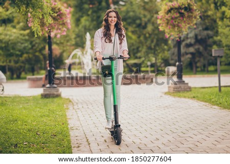 Full body photo of pretty young woman happy smile enjoy ride electric scooter spring time in park
