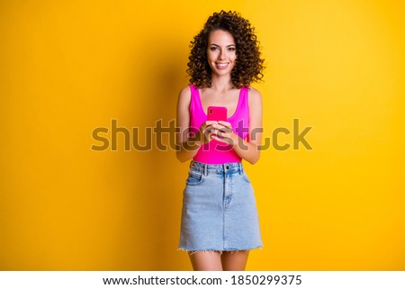 Photo of charming pretty lady good mood hold telephone hands vacation youth millennial party popular bloggers wear pink singlet tank-top denim skirt isolated shine yellow color background