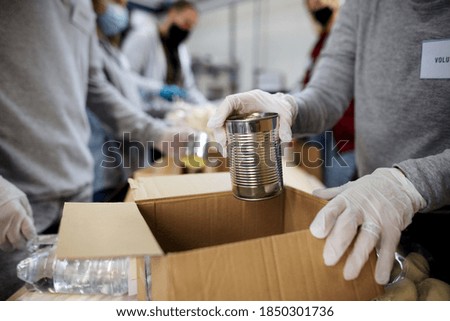 Midsection of group of volunteers in community donation center, food bank and coronavirus concept. Royalty-Free Stock Photo #1850301736