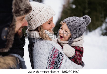 Father and mother with small child in winter nature, standing in the snow. Royalty-Free Stock Photo #1850304460