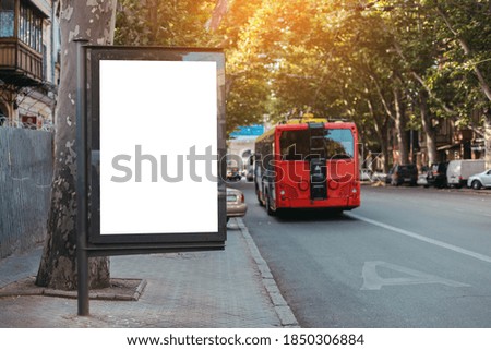 Vertical billboard lightbox mock up for advertisement, banner near street road. Red bus travels on a dedicated line in the city