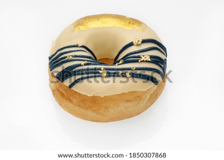 Ring donut with flesh color icing on top is topped with blue icing into long line of gold and gold shimmer, isolated on white back ground.