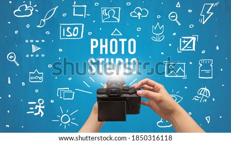 Hand taking picture with digital camera and PHOTO STUDIO inscription, camera settings concept