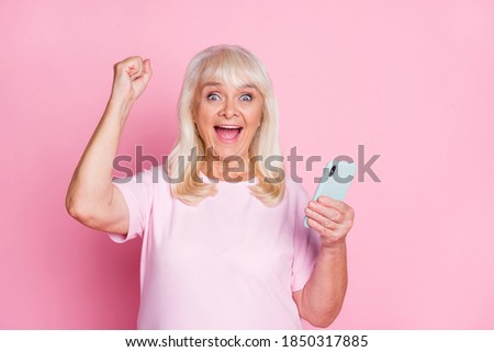 Photo portrait of crazy granny keeping smartphone gesturing like winner shouting isolated on pastel pink color background