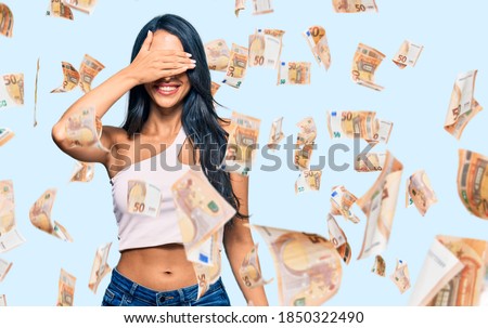 Beautiful hispanic woman wearing casual clothes smiling and laughing with hand on face covering eyes for surprise. blind concept.